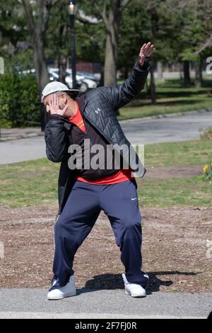 Un uomo conduce una lezione di Zumba attraverso un vigoroso allenamento di danza in un parco a Queens, New York City. Foto Stock