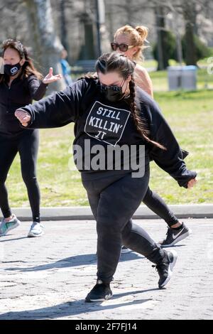 Una donna con i pigtail e una felpa 'STILL KILLIN' IT' frequenta una vigorosa lezione di danza Zumba inQueens, New York City. Foto Stock