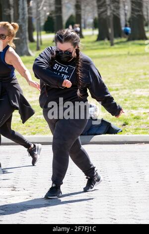 Una donna con i pigtail e una felpa 'STILL KILLIN' IT' frequenta una vigorosa lezione di danza Zumba inQueens, New York City. Foto Stock