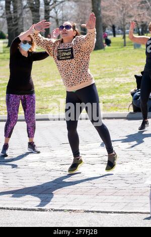 Una donna conduce una classe di Zumba attraverso un vigoroso allenamento di danza in un parco a Queens, New York City. Foto Stock