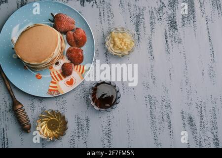 Frittelle fatte in casa con fragole fresche. Cucchiaia di miele, miele, marmellata. Vista dall'alto Foto Stock