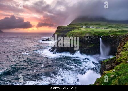 Tramonto alla cascata e scogliere di Gasadalur, Isole Faroe, Danimarca, Europa Foto Stock