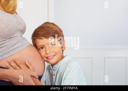 Ragazzo ascolta il bambino con l'orecchio sul ventre della madre incinta Foto Stock