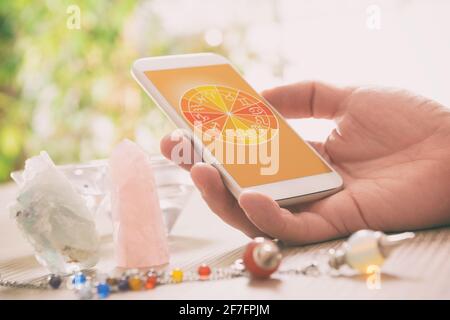 Segni zodiacali e smart phone in mano. Concetto moderno di astrologia. Foto Stock
