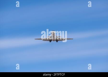 Business jet atterrando contro il cielo blu Foto Stock