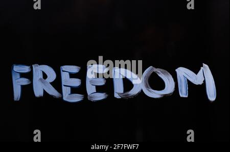 Messaggio scritto a mano di indipendenza o di motivazione della libertà 'libertà'. Messaggio di testo "libertà" sul vetro utilizzando pennello e vernice. Sfondo nero. Foto di alta qualità Foto Stock