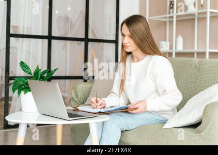 Donna scrive in notebook con notebook Foto Stock