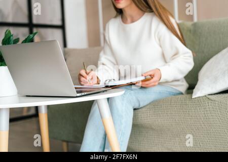 Donna scrive in notebook con notebook Foto Stock