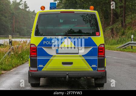 Vista posteriore di un'auto di polizia sull'autostrada in una baia di parcheggio di emergenza. Tempo piovoso con alberi sullo sfondo. Luci blu sul tetto e giallo A. Foto Stock