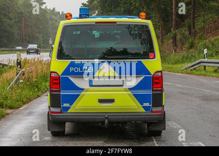 Vista posteriore di una radio pattuglia dall'autostrada del Brandeburgo in una baia di arresto di emergenza. Macchina di polizia in vernice gialla e blu su una strada bagnata. Foto Stock