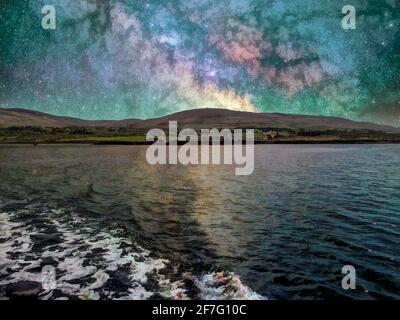 Notte stellata sulla baia del mare con colline all'orizzonte. Foto Stock