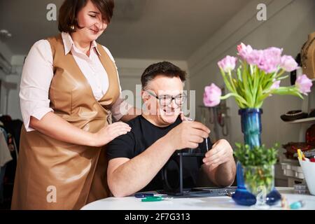 Donna che guarda un gioioso handcrafter creare una nuova collana Foto Stock