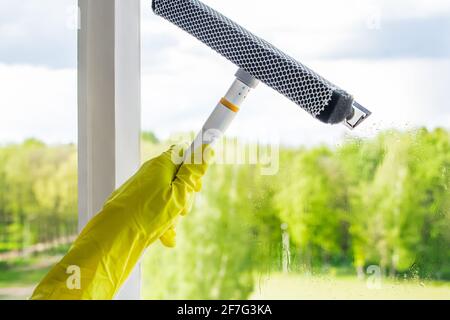 Finestre di lavaggio. Una giovane donna spruzza un detergente e pulisce il bicchiere. Concetto di pulizia domestica. Foto Stock