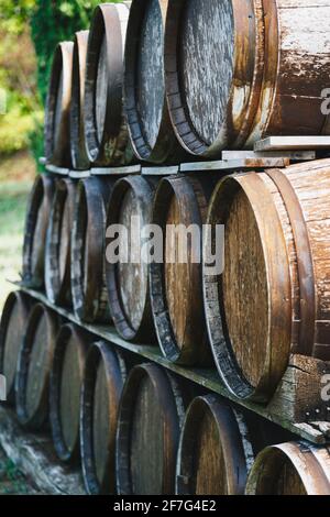 Primo piano di vecchie botti di vino in legno accatastate all'esterno di una cantina su vigneto Foto Stock