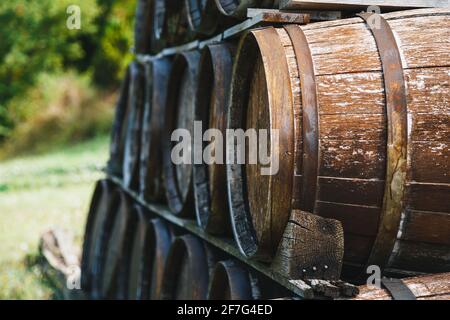 Primo piano di vecchie botti di vino in legno accatastate all'esterno di una cantina su vigneto Foto Stock