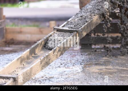 Colata di lastre di calcestruzzo. Il calcestruzzo viene drenato attraverso un vassoio di legno realizzato localmente da un betoniera. Foto Stock