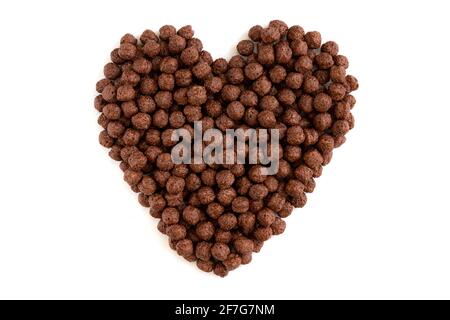 cuore fatto di palle croccanti di mais al cioccolato isolate su sfondo bianco, palle croccanti di cereali al cioccolato per colazione, cibo gustoso Foto Stock