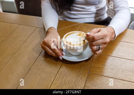 Un cliente in un caffè stigla lo zucchero in una tazza di caffè. Il concetto di fast food. Foto Stock