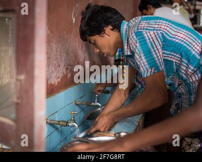 Varanasi, India. 10-16-2019. Adolescenti maschi che lavano il piatto e il cucchiaio dopo pranzo a scuola a Varanasi. Foto Stock