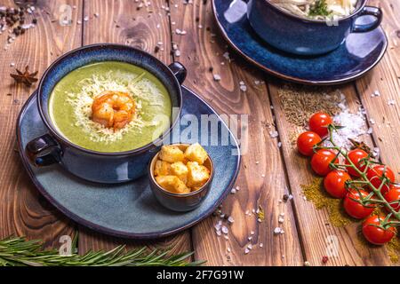 Zuppa di purè con gamberi, crostini e pomodori ciliegini su fondo di legno marrone decorata con spezie, rosmarino, sale grosso. Vista dall'alto. Foto Stock
