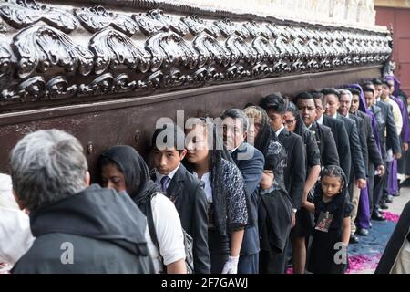 Gli uomini ben vestiti in abiti e le donne in abbigliamento tradizionale partecipano alla solenne processione Semana Santa ad Antigua, Guatemala. Foto Stock