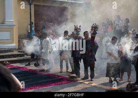 Le donne indigene guatemalteche in abiti tradizionali bruciano incenso durante la processione Semana Santa ad Antigua, un solenne rituale intriso di storia. Foto Stock