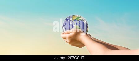 Ambiente giorno concetto, Globe in mani su sfondo blu cielo. Salvare la terra. Elementi di questa immagine forniti dalla NASA Foto Stock