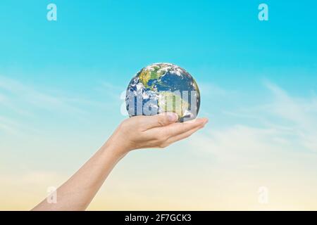 Globo nelle mani sopra lo sfondo blu del cielo. Salvare la terra. Elementi di questa immagine forniti dalla NASA Foto Stock