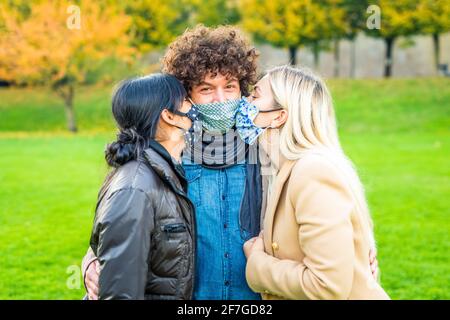 Ritratto dei giovani di amici che si baciano in città parcheggia come sfondo indossando maschere di protezione viso.prevenzione Coronavirus, viaggio sicuro Foto Stock