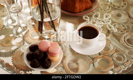 Tavolo di vetro con una tazza di caffè, macaron dolci. Foto Stock