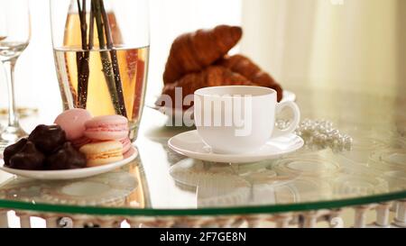 Tavolo in vetro con una tazza di caffè, croissant dolci Foto Stock