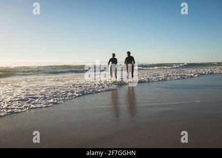 Felice coppia afroamericana che porta tavole da surf in riva al mare Foto Stock