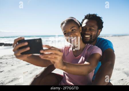 Felice coppia afroamericana sulla spiaggia in riva al mare prendendo selfie Foto Stock