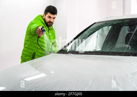 lavare la vettura spruzzando acqua ad alta pressione tubo flessibile con schiuma Foto Stock