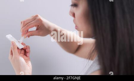 Giovane donna esegue un test di auto antigene Covid-19 Foto Stock