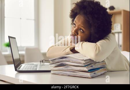 Giovane operaio afroamericano che sogna di appoggiarsi alla testa sulla carta impilare Foto Stock