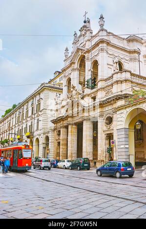 La trafficata Via po, con traffico intenso, tram arancione luminoso e la chiesa di Santissima Annunziata, Torino, Italia Foto Stock