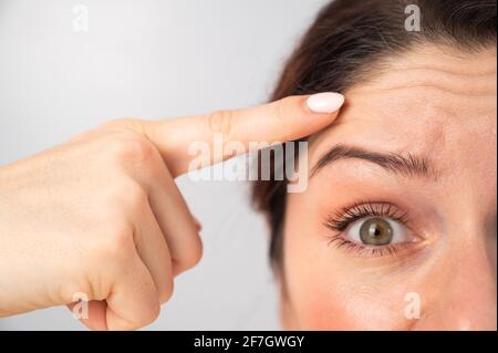 Ritratto in primo piano di una donna caucasica di mezza età che mostra rughe sulla fronte. Segni di invecchiamento sul viso Foto Stock