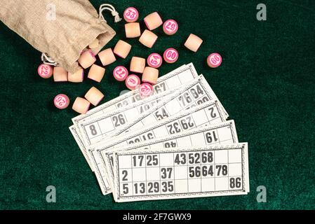 Lotto, un classico gioco da tavolo per famiglie. Botti di legno in juta e tessere su superficie di velluto verde. Vintage game, bingo. Foto Stock