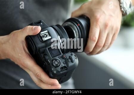 Mani maschili che indossano l'obiettivo professionale della fotocamera digitale moderna Foto Stock