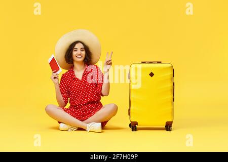 donna con valigia in viaggio su sfondo giallo. Foto Stock