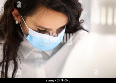 Donna in maschera protettiva ha abbassato il viso da vicino Foto Stock