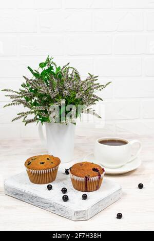 Cupcake con ribes nero e foglie di menta su un piatto bianco. Messa a fuoco selettiva. Foto Stock