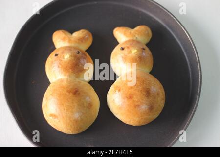 Panini di Pasqua fatti in casa. Conigli cotti a forma di coniglietto come parte della celebrazione pasquale. Scatto su sfondo bianco Foto Stock