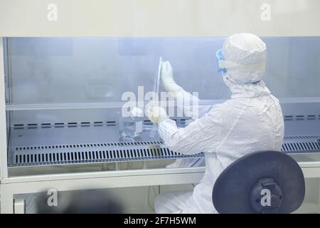 Gli scienziati di laboratorio indossano indumenti protettivi che svolgono ricerche mediche in un laboratorio scientifico. Foto Stock