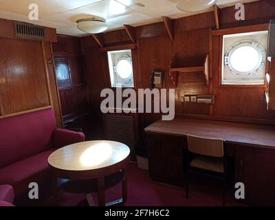 Gdansk, Polonia - 07 maggio 2020: Cabina con area salotto congestionata, telefono vintage con finestra rotonda all'interno della nave SS Soldek, parte della ma polacca Foto Stock