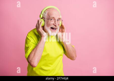 Foto di profilo di ridere ottimista vecchio ascoltare musica indossare le cuffie occhiali indossano abiti di colore verde isolati su sfondo rosa Foto Stock