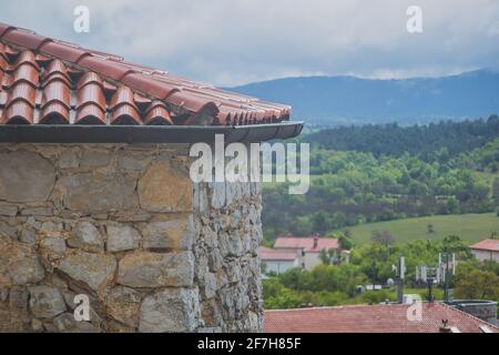 Particolare di una delle tipiche case carsiche di Stanjel in Slovenia in una giornata nuvolosa di primavera, guardando attraverso la finestra verso la casa e il paesaggio piovoso Foto Stock