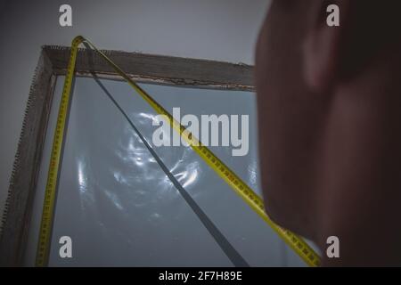 Una persona che misura la larghezza e l'altezza dell'apertura di una porta con un metro a nastro giallo. Misurazioni della costruzione di nuove case Foto Stock