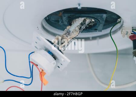 Estrazione di un riscaldatore elettrico dalla caldaia o dal riscaldatore dell'acqua per rimuovere i residui di calcare su di esso come parte di una manutenzione. Termostato elettrico in fase di rimozione Foto Stock